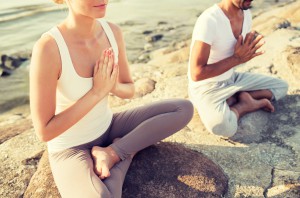 fitness, sport, people and lifestyle concept - close up of couple making yoga exercises sitting on pier outdoors